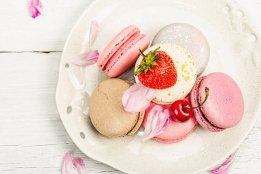 Beyaz ahşap bir arka planda çilekli, kirazlı ve şakayıklı çiçek yaprakları. Tatlı tatlı, romantik tarzı, düz yatış, sert ışık, koyu gölge, üst manzara