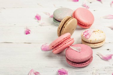 Beyaz ahşap arka planda şakayık çiçekli makarna. Tatlı, renkli ve pastel renkler. Romantik tarz, şenlik kartı, düz döşeme, kopyalama alanı