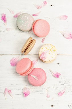 Beyaz ahşap arka planda şakayık çiçekli makarna. Tatlı, renkli ve pastel renkler. Romantik tarz, şenlik kartı, düz yatak, üst görünüm