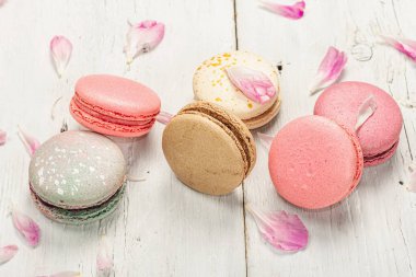 Beyaz ahşap arka planda şakayık çiçekli makarna. Tatlı, renkli ve pastel renkler. Romantik tarz, şenlik kartı, düz yatak, yakın çekim