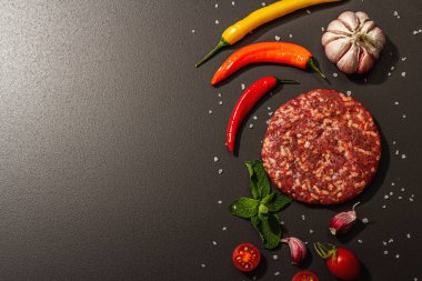 Siyah taşlı arka planda kıymalı biftek pirzolası. Taze sebze, nane ve baharat. Modern sert ışık, karanlık gölge, düz uzanma, üst manzara