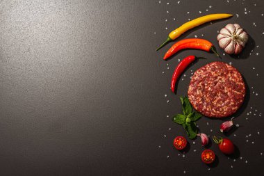 Siyah taşlı arka planda kıymalı biftek pirzolası. Taze sebze, nane ve baharat. Modern sert ışık, karanlık gölge, düz uzanma, üst manzara