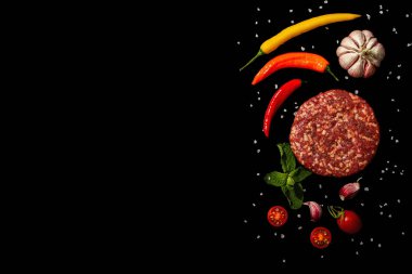 Siyah arka planda izole edilmiş kıymalı biftekten çiğ pirzola. Taze sebze, nane ve baharat. Modern sert ışık, karanlık gölge, düz uzanma, üst manzara