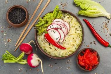 Sebzeli ve otlu Asya eriştesi. Geleneksel sebze çorbası ve çorba. Taş zemin, düz zemin, üst manzara