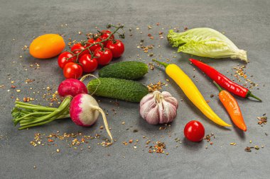 Yemek malzemeleri arka planında. Baharatlar, sebzeler, sarımsak, renkli biber ve salatalık. Taş beton arka plan, hazır gıda konsepti