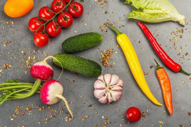 Yemek malzemeleri arka planında. Baharatlar, sebzeler, sarımsak, renkli biber ve salatalık. Taş beton arka plan, hazır yiyecek konsepti, düz alan, üst manzara