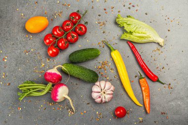 Yemek malzemeleri arka planında. Baharatlar, sebzeler, sarımsak, renkli biber ve salatalık. Taş beton arka plan, hazır yiyecek konsepti, düz alan, üst manzara