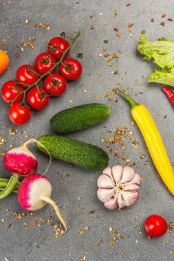 Yemek malzemeleri arka planında. Baharatlar, sebzeler, sarımsak, renkli biber ve salatalık. Taş beton arka plan, hazır yiyecek konsepti, düz alan, üst manzara