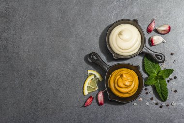 Hardal ve mayonez sosu. Taze nane, limon, sarımsak ve baharat. Sert bir ışık, karanlık bir gölge, taş beton bir zemin, düz bir zemin, üst manzara.