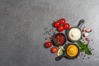 Hardal, ketçap ve mayonez sosu. Taze nane, limon, sarımsak ve baharat. Sert bir ışık, karanlık bir gölge, taş beton bir zemin, düz bir zemin, üst manzara.