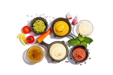 Beyaz arka planda izole edilmiş soslar ve taze sebzeler. Ketçap, hardal, mayonez, wasabi, tatlı köri ve barbekü. Baharatlar ve otlar, modaya uygun sert ışık, karanlık gölge, üst manzara