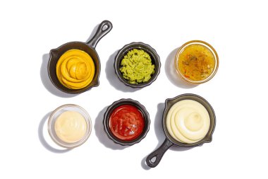 Beyaz arka planda izole edilmiş soslar ve taze sebzeler. Ketçap, hardal, mayonez, wasabi, tatlı köri ve barbekü. Baharatlar ve otlar, modaya uygun sert ışık, karanlık gölge, üst manzara