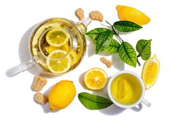 Olgun meyveli limon çayı ve beyaz arka planda taze yapraklar. Sıcak içecek, sert ışık, koyu gölge, düz uzanma, üst manzara