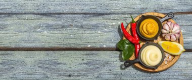 Hardal ve mayonez sosu. Taze nane, limon, sarımsak ve baharat. Sert bir ışık, koyu gölge, ahşap tahta arka plan, düz döşeme, pankart biçimi