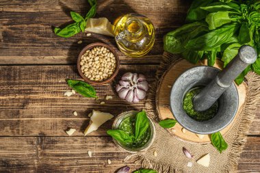 Ev yapımı İtalyan fesleğenli pesto sosu. Kaliteli havan topuzlu. Taze yaprak, parmesan, çam fıstığı ve zeytinyağı. Modaya uygun sert ışık, karanlık gölge, eski ahşap arka plan, üst manzara