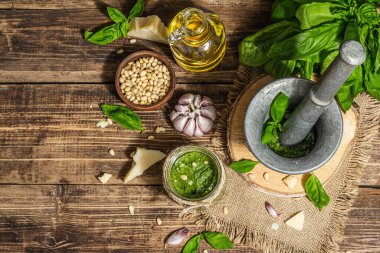 Ev yapımı İtalyan fesleğenli pesto sosu. Kaliteli havan topuzlu. Taze yaprak, parmesan, çam fıstığı ve zeytinyağı. Modaya uygun sert ışık, karanlık gölge, eski ahşap arka plan, üst manzara