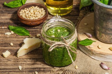 Ev yapımı İtalyan fesleğenli pesto sosu. Kaliteli havan topuzlu. Taze yaprak, parmesan, çam fıstığı ve zeytinyağı. Modaya uygun sert ışık, karanlık gölge, eski ahşap arka plan, kapat