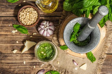 Ev yapımı İtalyan fesleğenli pesto sosu. Kaliteli havan topuzlu. Taze yaprak, parmesan, çam fıstığı ve zeytinyağı. Modaya uygun sert ışık, karanlık gölge, eski ahşap arka plan, üst manzara