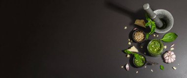 Antika havan topuzlu İtalyan fesleğen sosu hazırlama işlemi. Ev yapımı yemekler, geleneksel tarifler için malzemeler. Sert ışık, koyu gölge, siyah taş arkaplan, afiş biçimi