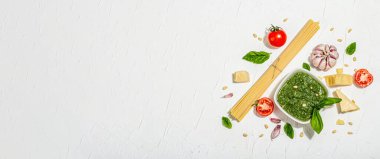 Klasik İtalyan makarnası hazırlamak için geleneksel malzemeler. Kuru spagetti, fesleğen pesto, domates, parmesan ve sarımsak. Modaya uygun sert ışık, koyu gölge, beyaz macun arkaplan, pankart biçimi