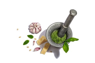 Beyaz arka planda izole edilmiş bir tokmağı olan havana batırılmış İtalyan fesleğen pesto sosu hazırlama süreci. Ev yapımı yemekler, geleneksel tarifler için malzemeler. Sert ışık, karanlık gölge