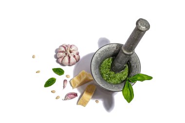 Beyaz arka planda izole edilmiş bir tokmağı olan havana batırılmış İtalyan fesleğen pesto sosu hazırlama süreci. Ev yapımı yemekler, geleneksel tarifler için malzemeler. Sert ışık, karanlık gölge