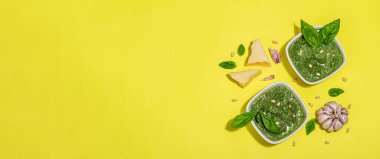 Çam fıstığı, parmesan ve sarımsaklı bir kasede pesto sosu. Parlak parlak ışık, koyu gölge, parlak sarı arkaplan