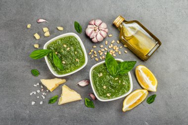 Çam fıstığı, parmesan ve sarımsaklı bir kasede pesto sosu. Geleneksel İtalyan yemekleri, gri taş arka plan, üst manzara.