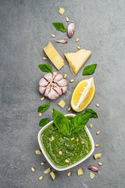 Pesto sauce in a bowls with pine nuts, parmesan and garlic. Traditional Italian food, grey stone concrete background, top view