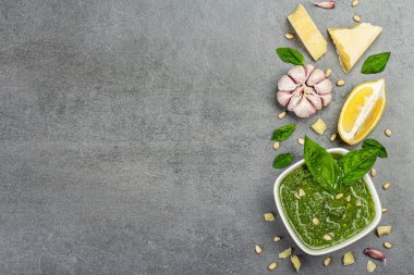Çam fıstığı, parmesan ve sarımsaklı bir kasede pesto sosu. Geleneksel İtalyan yemekleri, gri taş arka plan, üst manzara.