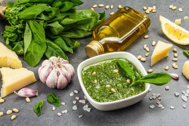 Çam fıstığı, parmesan ve sarımsaklı bir kasede pesto sosu. Geleneksel İtalyan yemekleri, gri taş beton zemin, pankart biçimi, kapat