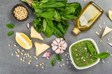 Çam fıstığı, parmesan ve sarımsaklı bir kasede pesto sosu. Geleneksel İtalyan yemekleri, gri taş beton zemin, pankart biçimi, üst görünüm