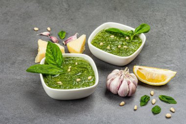 Çam fıstığı, parmesan ve sarımsaklı bir kasede pesto sosu. Geleneksel İtalyan yemekleri, gri taş beton zemin, pankart biçimi, kapat