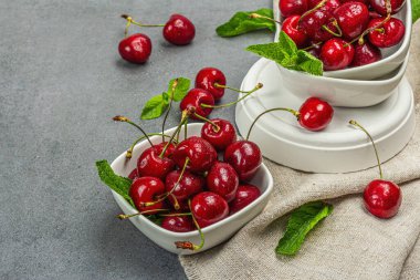 Taze nane yapraklı olgun kirazlar, geleneksel yaz meyveleri. Modaya uygun beton standları, kaliteli peçeteler. Gri taş beton zemin, kopyalama alanı