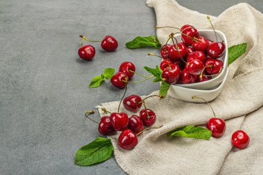 Taze nane yapraklı olgun kirazlar, geleneksel yaz meyveleri. Modaya uygun beton standları, kaliteli peçeteler. Gri taş beton zemin, kopyalama alanı