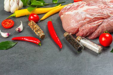 Baharatlı ve sebzeli çiğ domuz filetosu ve gri taşlı arka plan. Sağlıklı yemek, taze domates ve defne yaprağı pişirmek için geleneksel hayvan proteini. Mutfak somut kavramı, kopyalama alanı