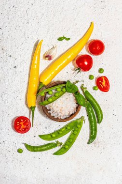 Hafif alçı arka planda çeşitli taze sebzeler ve baharatlar. Olgun sarı biber, domates, bezelye, salatalık, sarımsak, renkli biber. Sağlıklı yemek pişirmek için gerekli malzemeler, üst görünüm