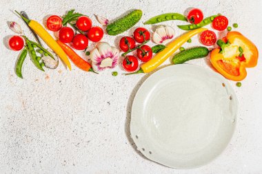 Vejetaryen sofrası. Olgun taze sebzeler, boş tabaklar, çatal bıçak takımı, baharatlar. Sert bir ışık, koyu gölge, aydınlık macun arkaplan, üst görünüm