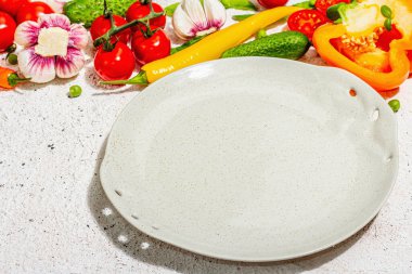 Vejetaryen sofrası. Olgun taze sebzeler, boş tabaklar, çatal bıçak takımı, baharatlar. Sert bir ışık, karanlık bir gölge, aydınlık macun arkaplan, kapat