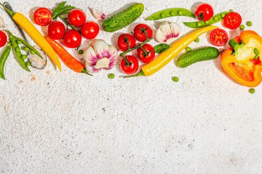 Hafif alçı arka planda çeşitli taze sebzeler ve baharatlar. Olgun sarı biber, domates, bezelye, salatalık, sarımsak, renkli biber. Sağlıklı yemek pişirmek için gerekli malzemeler, üst görünüm