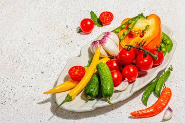 Servis tabağında taze sebze topla. Vejetaryen gıda konsepti, modaya uygun sert ışık, karanlık gölge. Hafif alçı arkaplan, kopyalama alanı