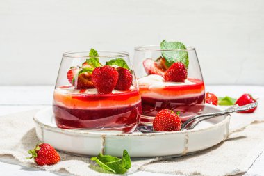 Italian dessert panna cotta in glass with strawberries. Healthy sweet food, trendy hard light, dark shadow. Rustic style concept, white wooden boards background, copy space
