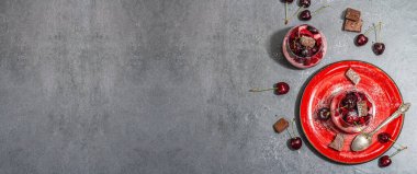 Delicious Italian dessert panna cotta with sweet cherry sauce, fresh berries and chocolate. Modern hard light, dark shadow, stone concrete background, banner format