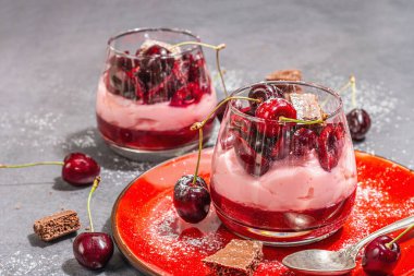 Delicious Italian dessert panna cotta with sweet cherry sauce, fresh berries and chocolate. Modern hard light, dark shadow, stone concrete background, close up