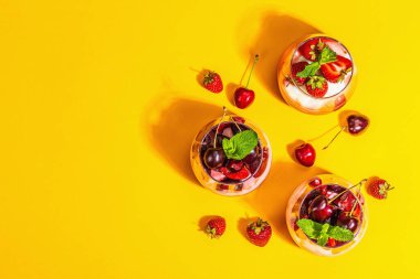Delicious Italian dessert panna cotta with sweet cherry sauce, strawberry jam, fresh berries and mint leaves. Trendy hard light, dark shadow, bright orange background, top view