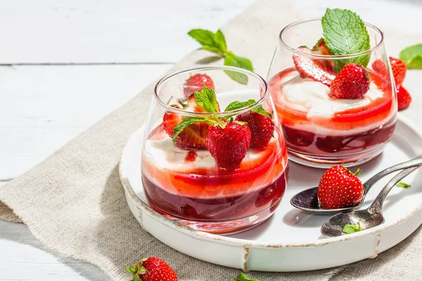 Italian dessert panna cotta in glass with strawberries. Healthy sweet food, trendy hard light, dark shadow. Rustic style concept, white wooden boards background, copy space
