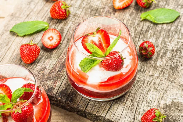 Italian dessert panna cotta in glass with strawberries. Healthy sweet food, trendy hard light, dark shadow. Rustic style concept, wooden boards background, close up