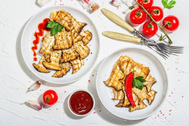 Fried slices Pleurotus eryngii mushrooms with sauce, spices and herbs. Healthy vegan food concept, hard light, dark shadowwhite plaster background, flat lay, top view