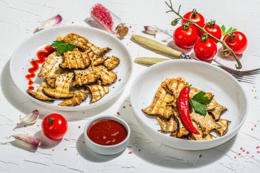 Fried slices Pleurotus eryngii mushrooms with sauce, spices and herbs. Healthy vegan food concept, hard light, dark shadowwhite plaster background, flat lay, close up