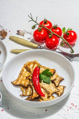 Fried slices Pleurotus eryngii mushrooms with sauce, spices and herbs. Healthy vegan food concept, hard light, dark shadowwhite plaster background, flat lay, copy space